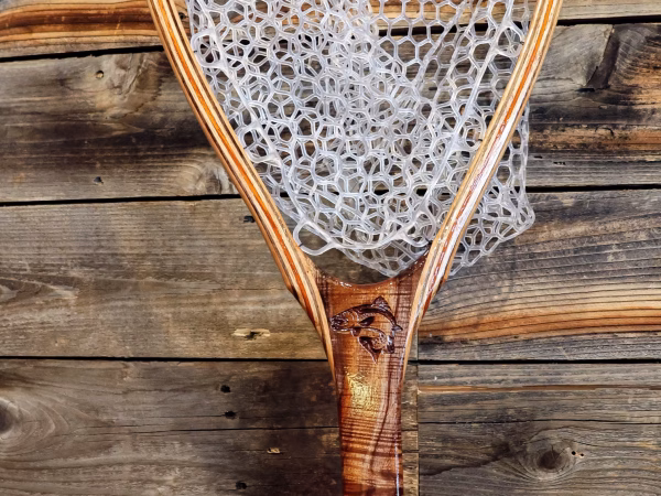 Trout carved into a fishing net with barnwood background.