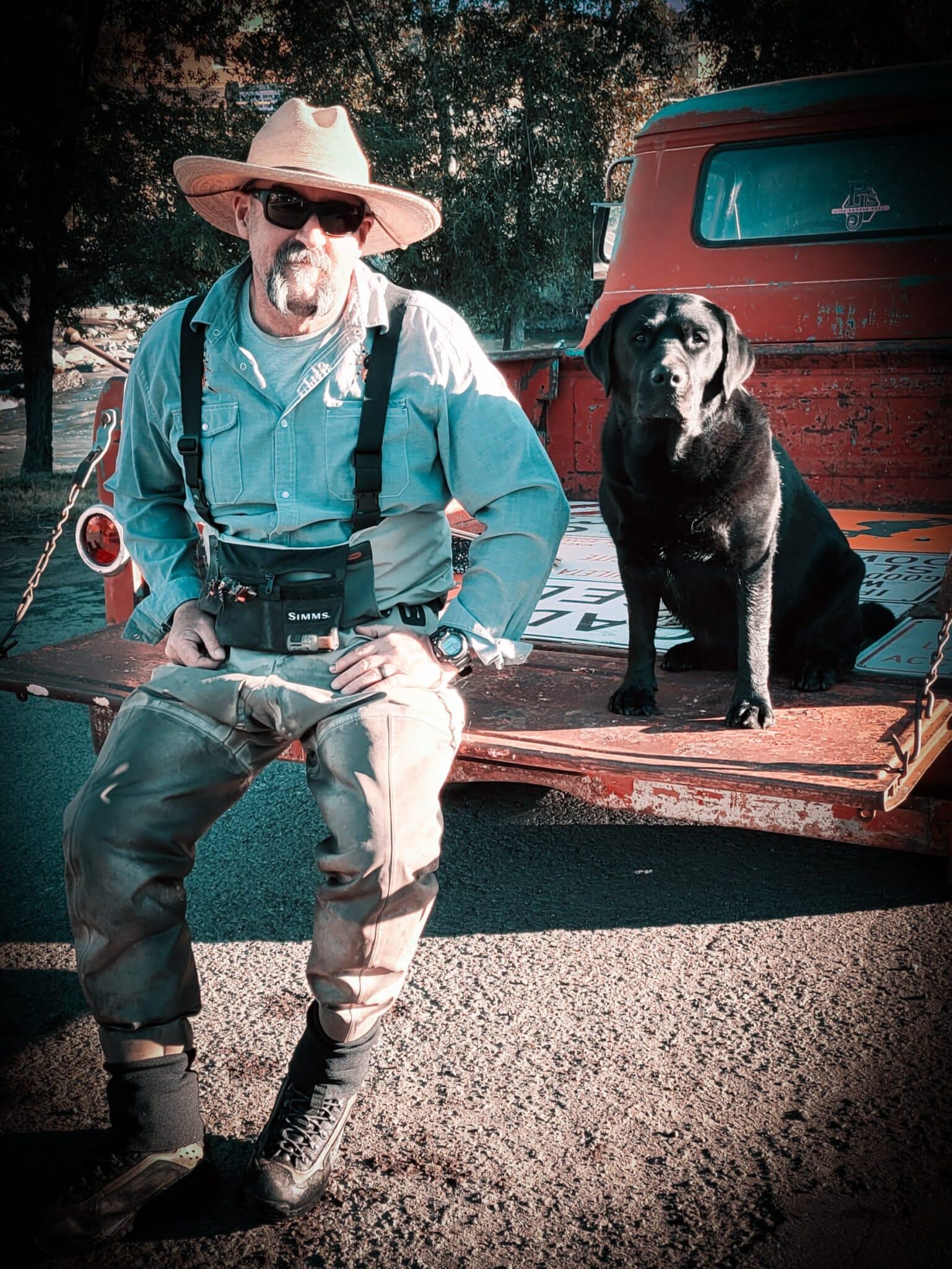 Paul and black lab on the tailgate of a vintage truck.