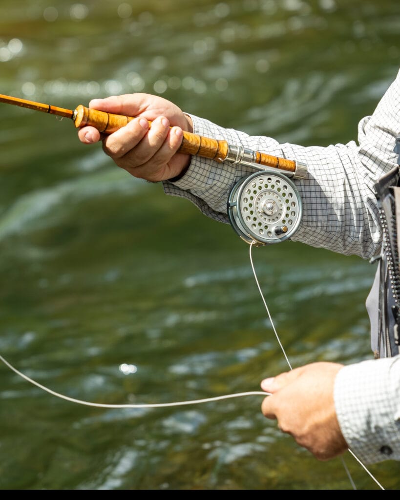 Man fishing with a bamboo fly rod in a river.