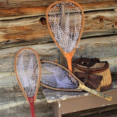 Three exotic wood fishing nets and vintage fishing creel on a bench.